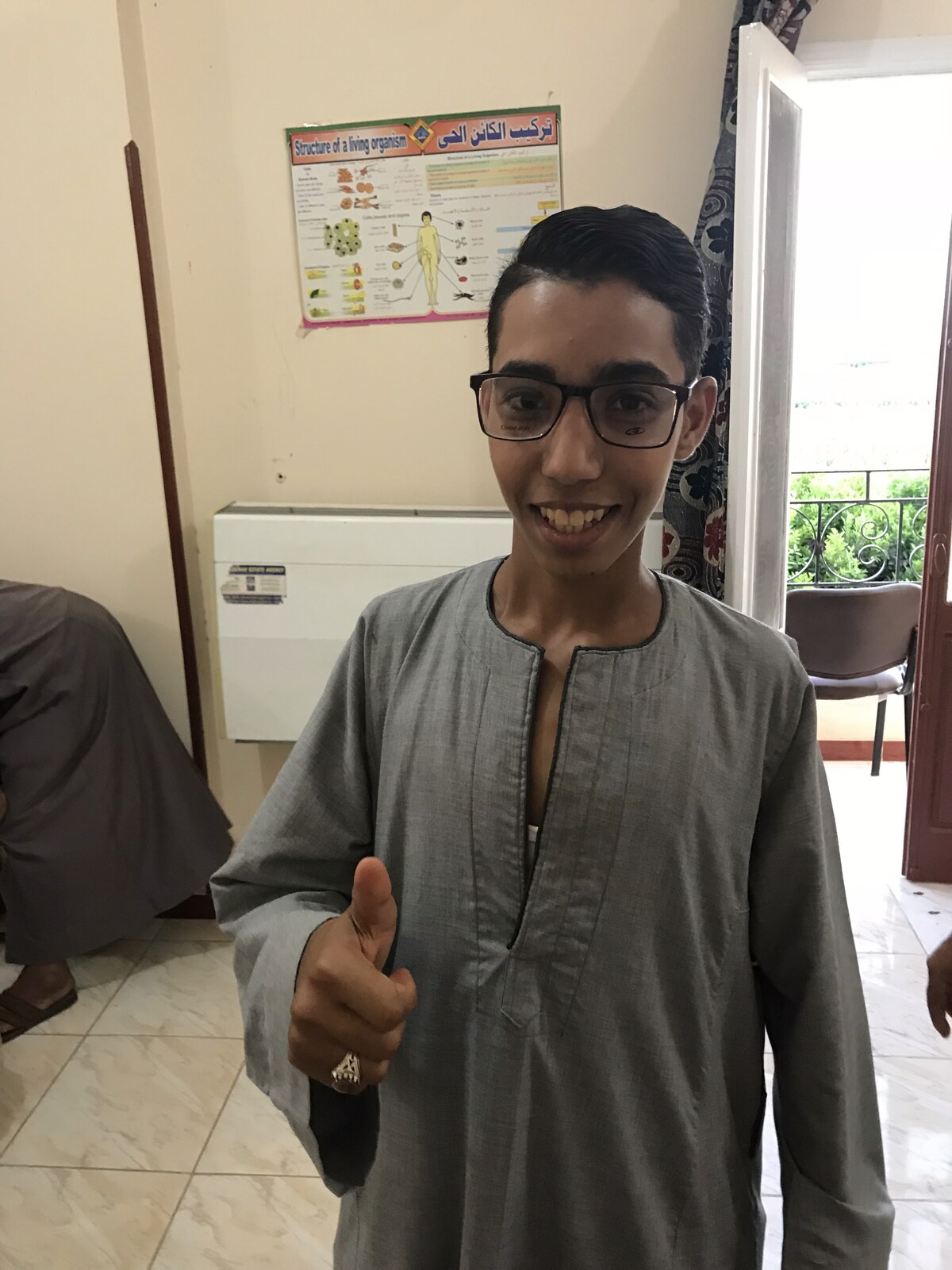 A smiling young man giving a thumbs up with his new glasses