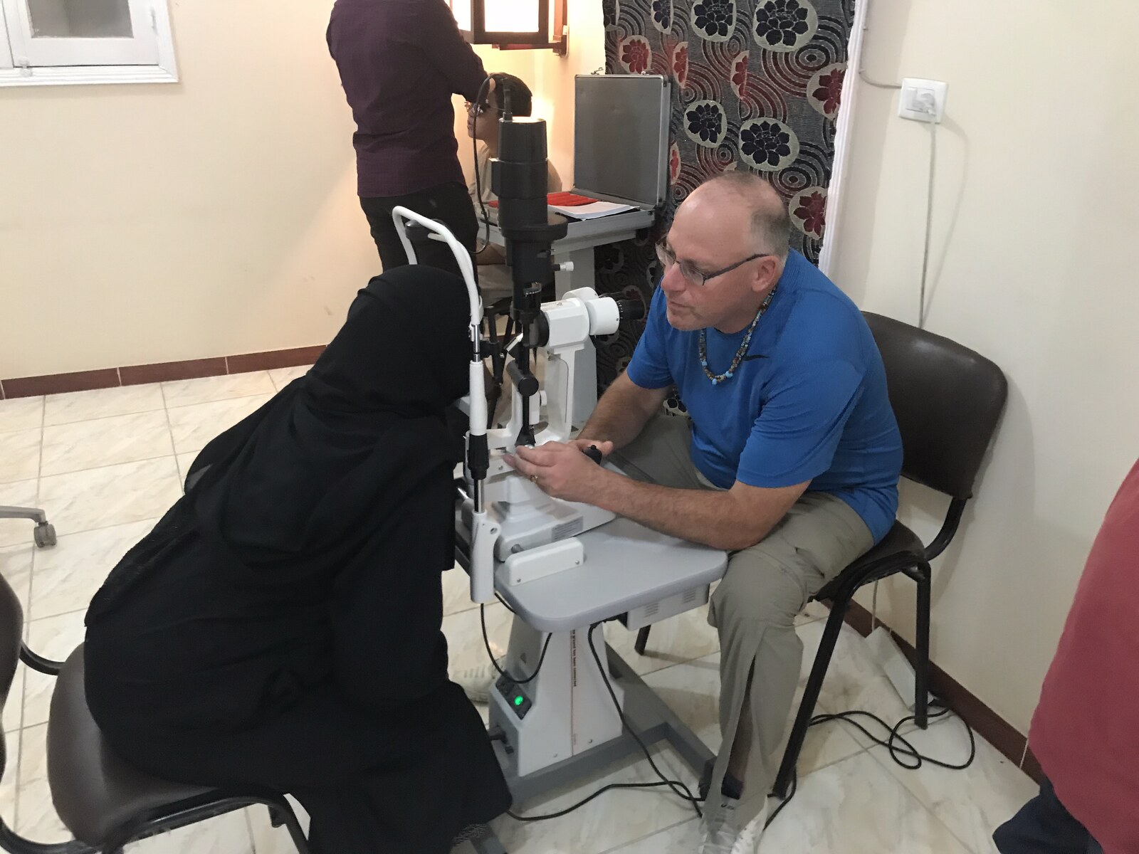 An optometrist examining a patient at the slit lamp