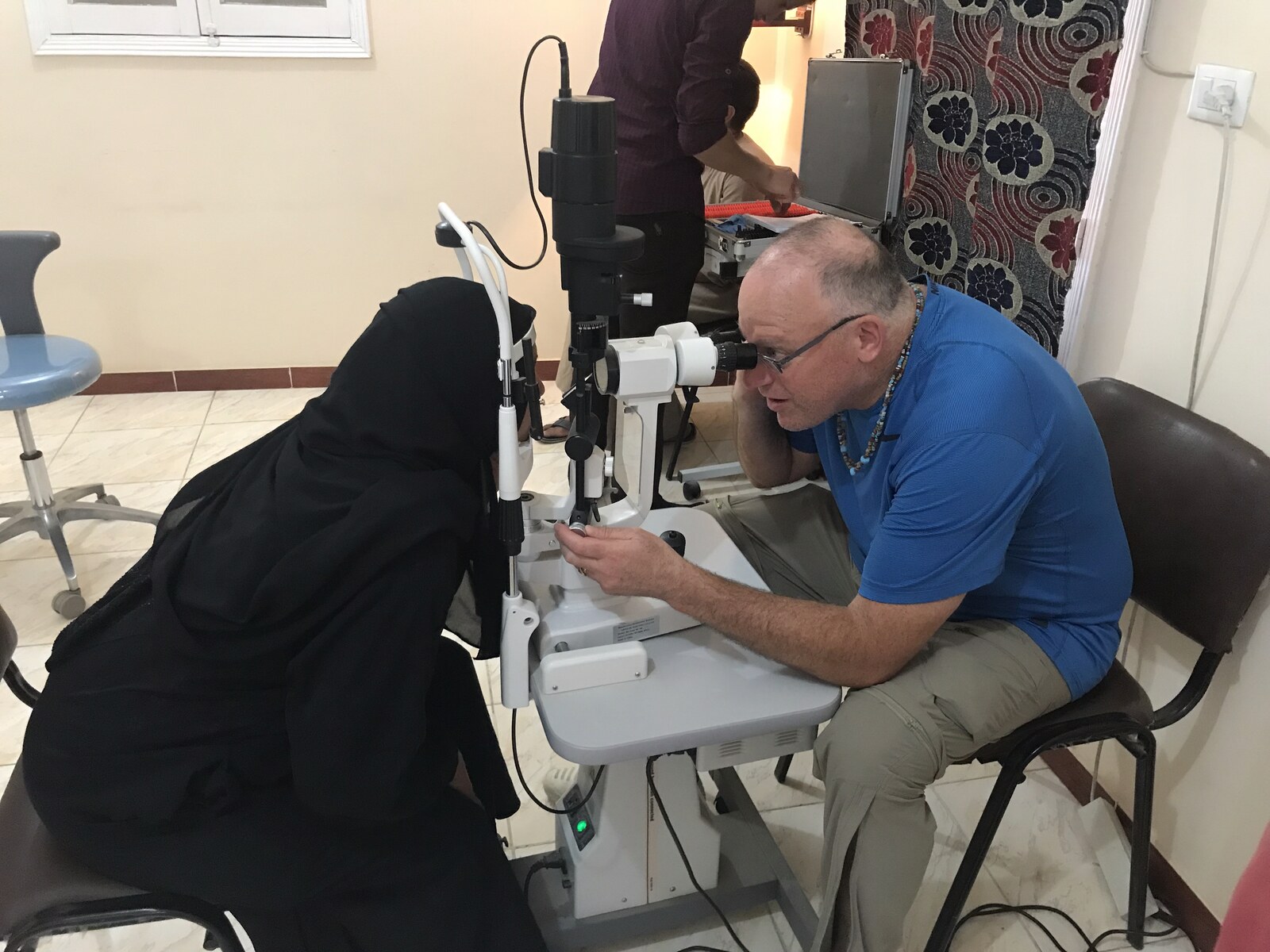 An optometrist performing an eye exam at the slit lamp