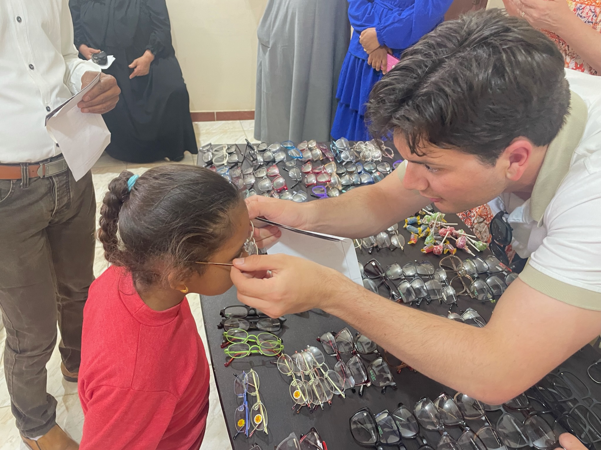 A volunteer fitting a child with eyeglasses